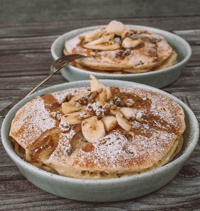 Three fluffy American pancakes with walnuts, caramelised banana and maple syrup